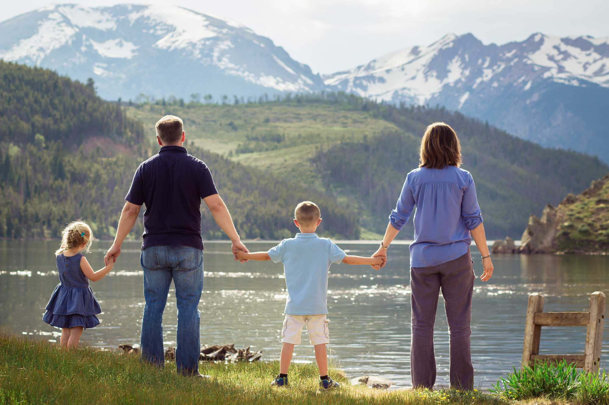 family-of-four-looking-into-mountains-holding-hands